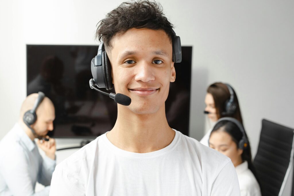 Professional call center agent wearing a headset, smiling confidently in a modern office setting.